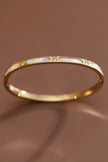 Gold bracelet with a subtle design on a brown background