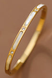 Gold bracelet with white stones on a brown background