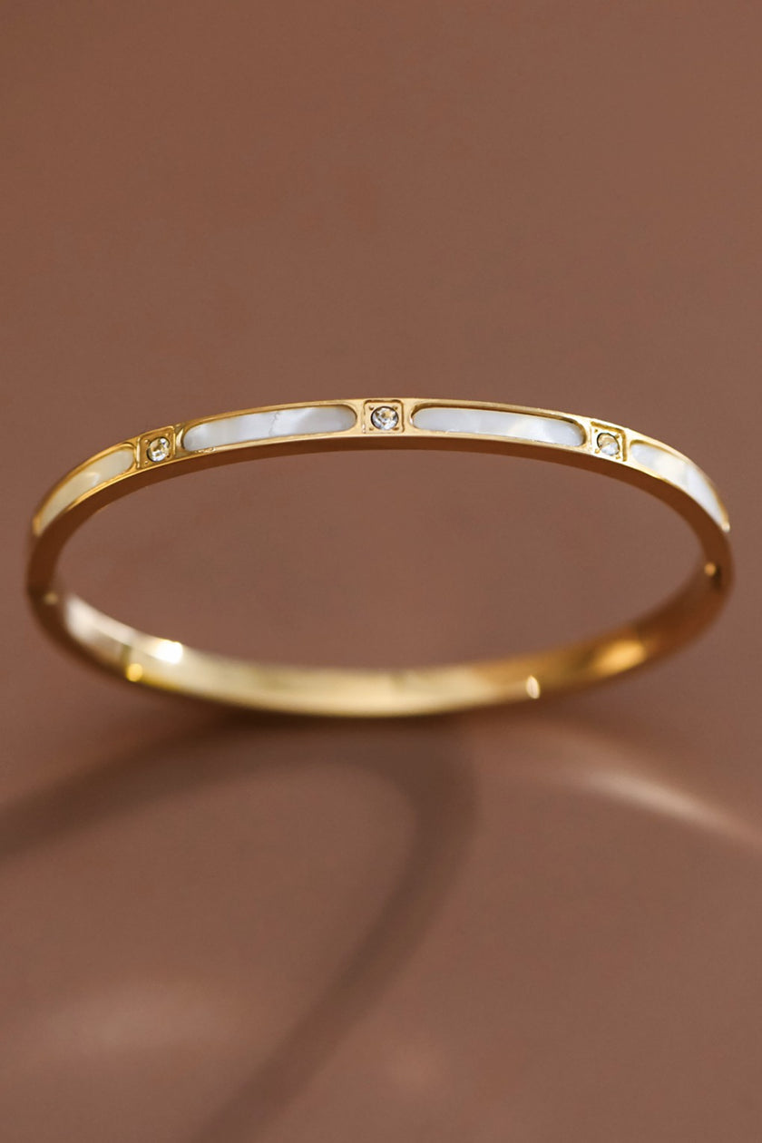 Gold bracelet with a subtle design on a brown background