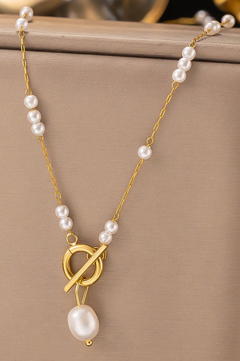 Pearl necklace with a gold clasp on a beige background