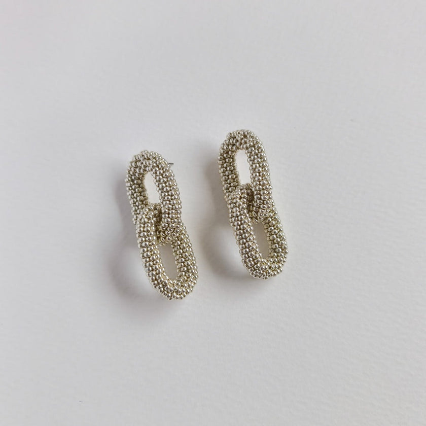 Pair of silver chainmail earrings on a light gray background