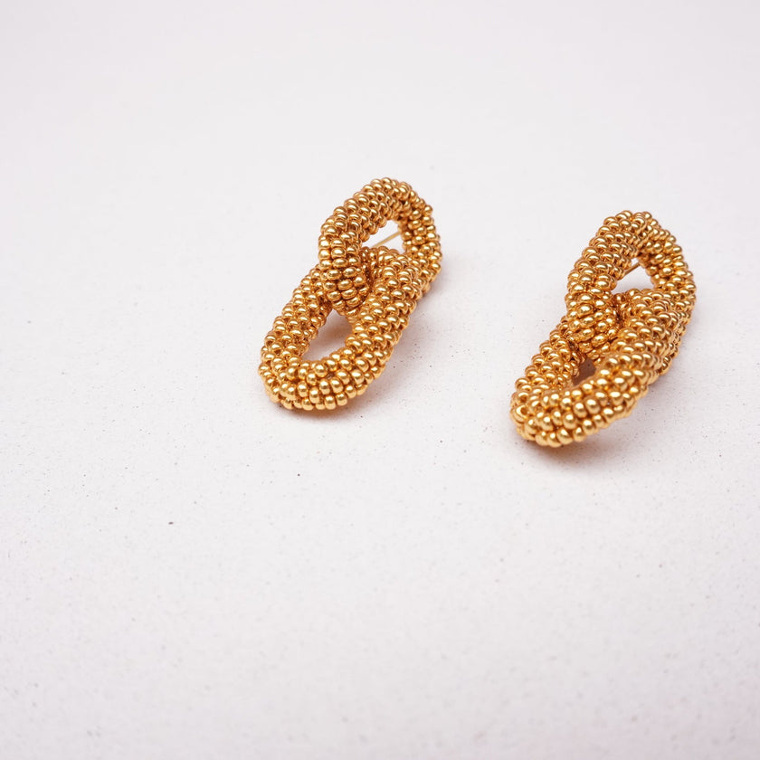 Pair of gold beaded earrings on a white background