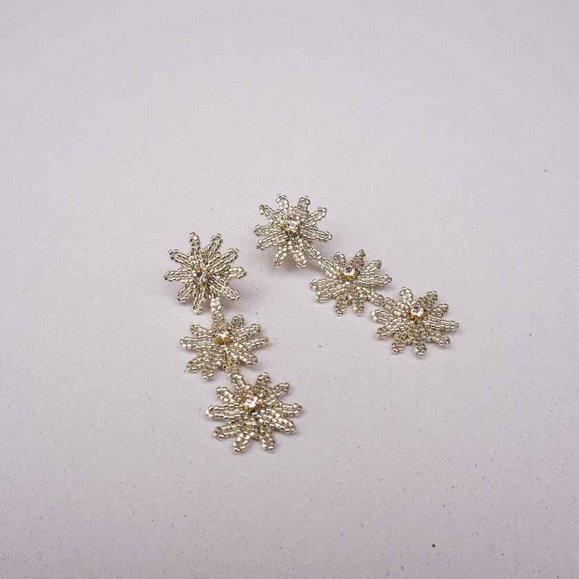 Silver snowflake-shaped earrings on a light gray background