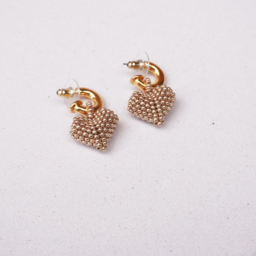 Pair of gold beaded earrings on a light gray background