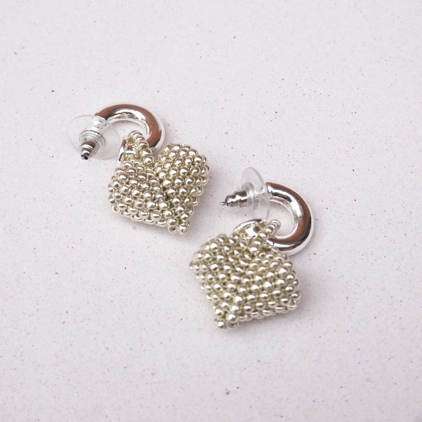 Pair of silver beaded earrings on a light gray background
