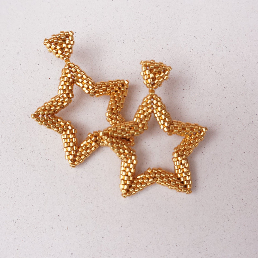 Gold star-shaped earrings on a light gray background