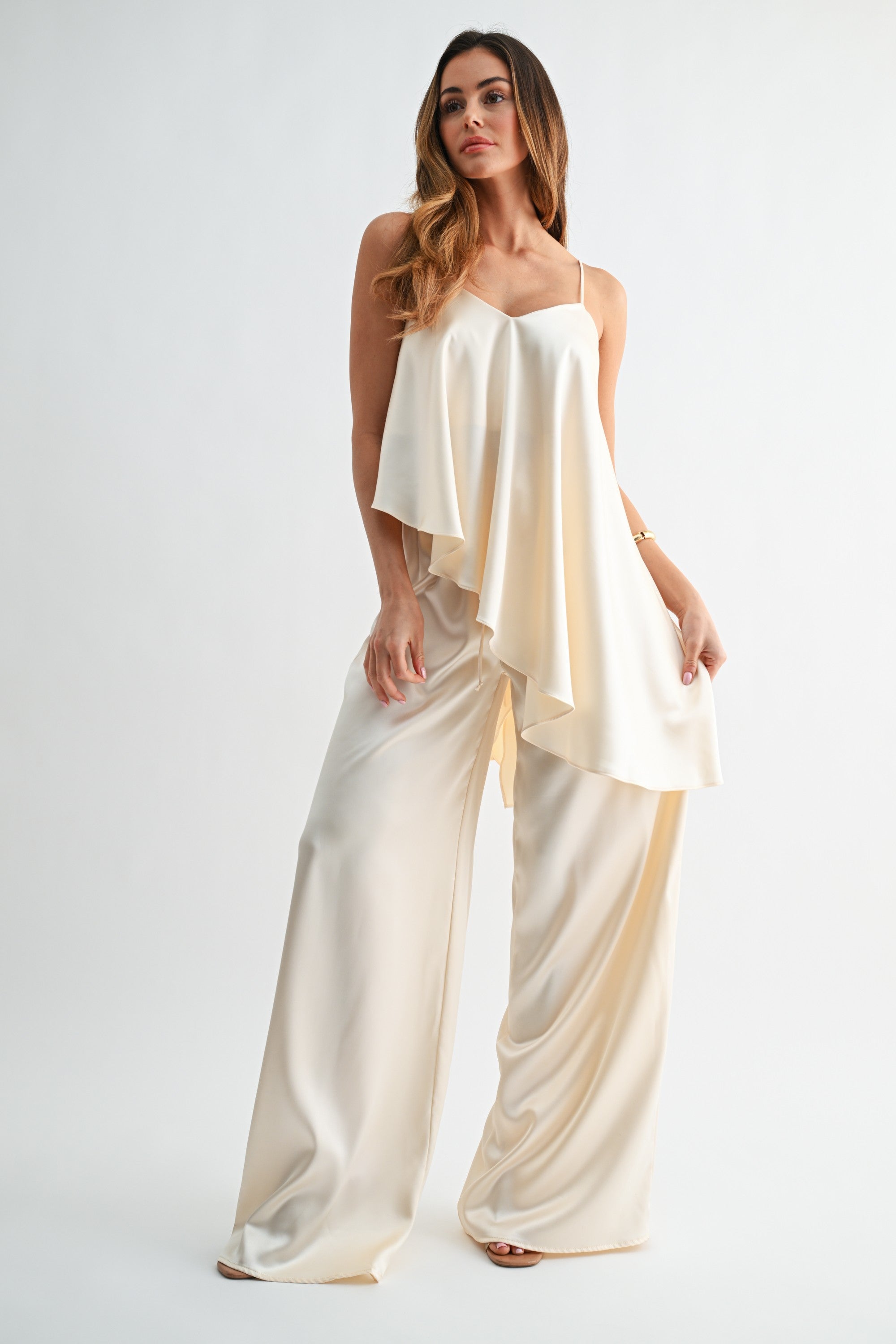 Woman wearing a cream-colored jumpsuit on a white background