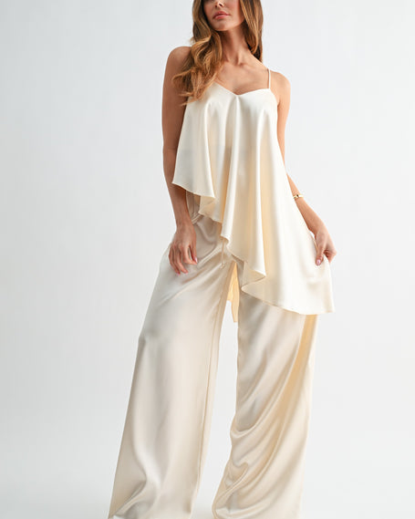 Woman wearing a cream-colored jumpsuit on a white background