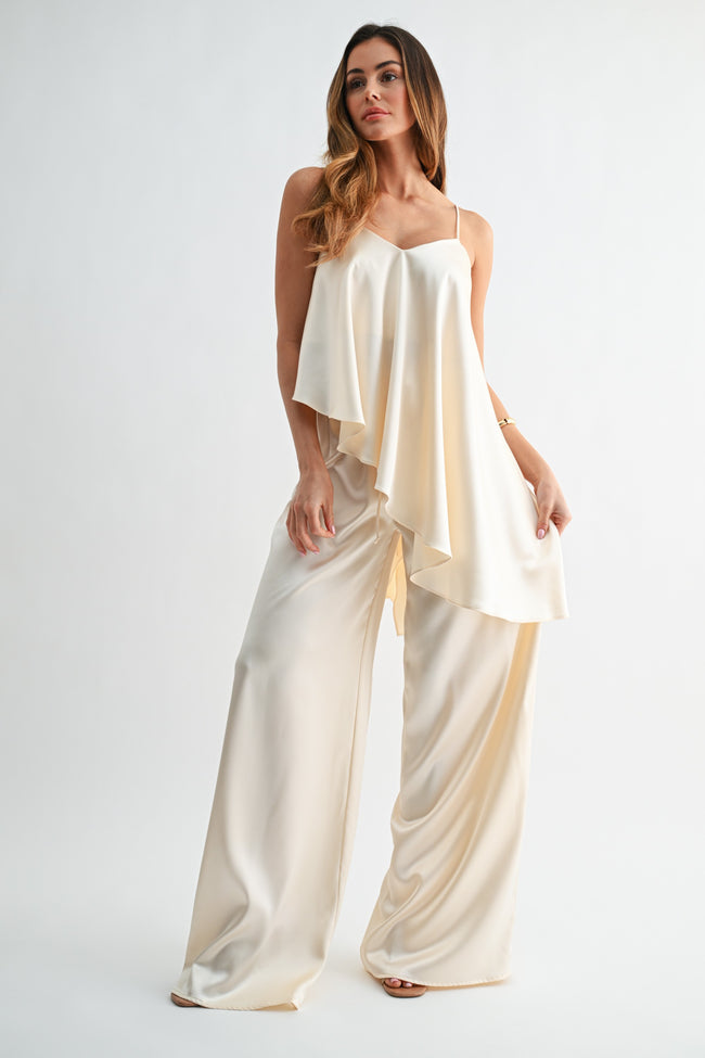 Woman wearing a cream-colored jumpsuit on a white background