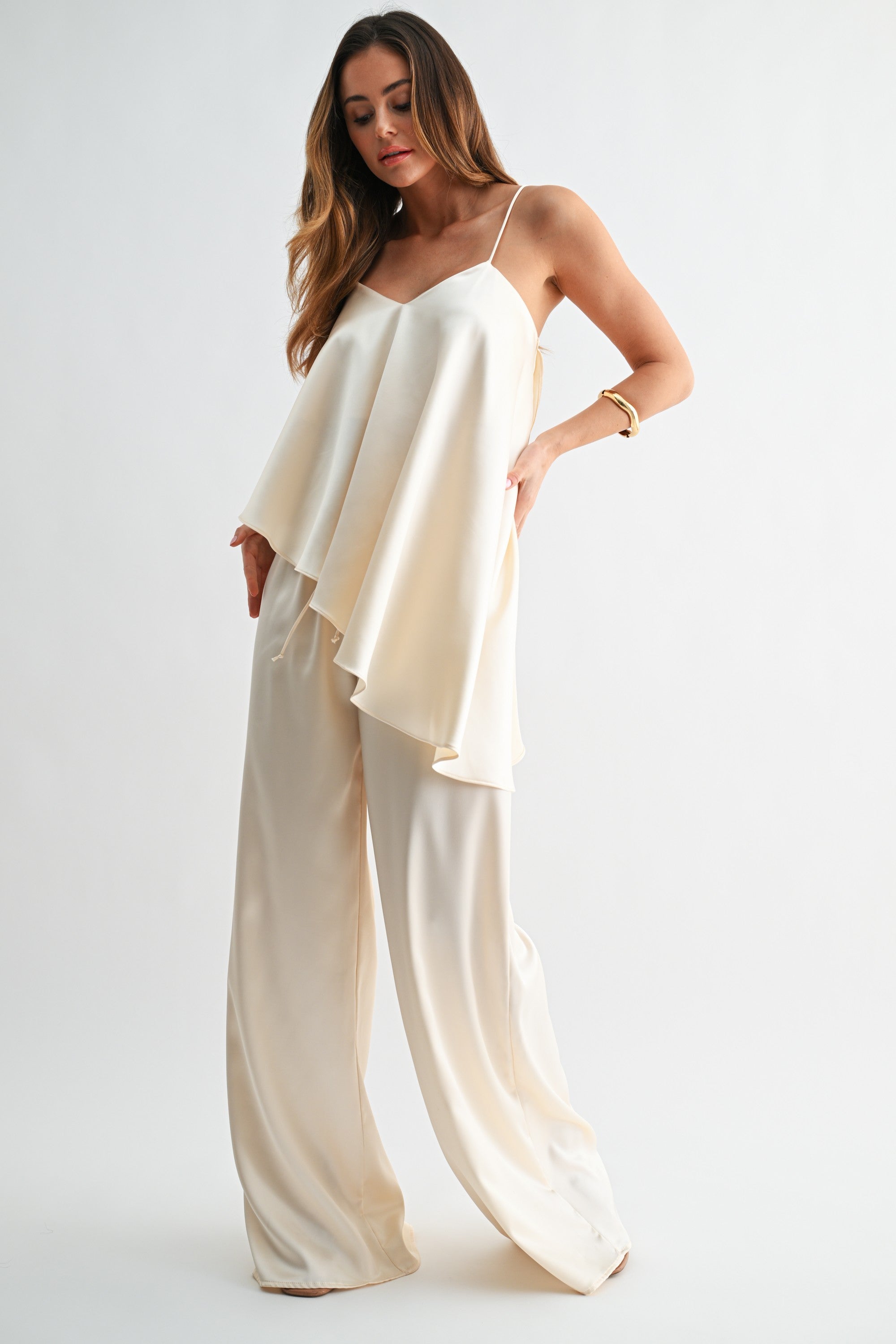 Woman wearing a cream-colored top and wide-leg pants on a white background